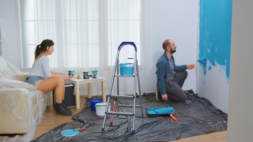 Villa Painting Service 2 couple conversation home renovation roller brush dipped blue paint apartment redecoration home construction while renovating improving repair decorating