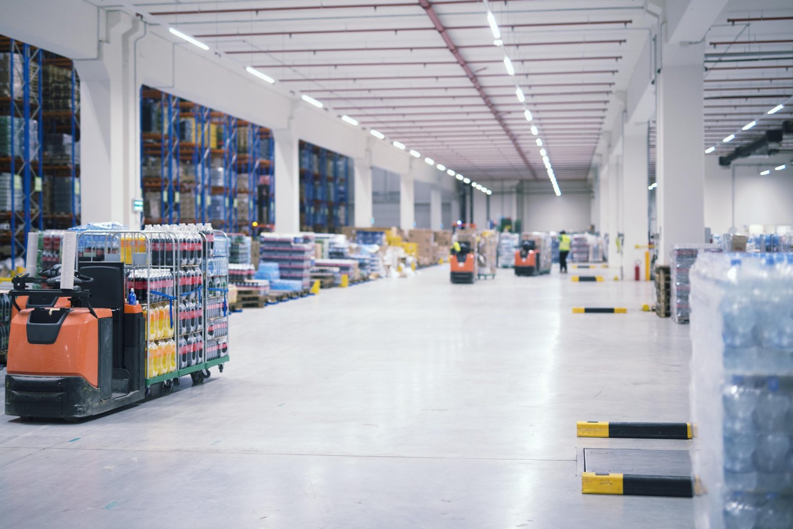 warehouse-industrial-building-interior-with-people-forklifts-handling-goods-storage-area-min